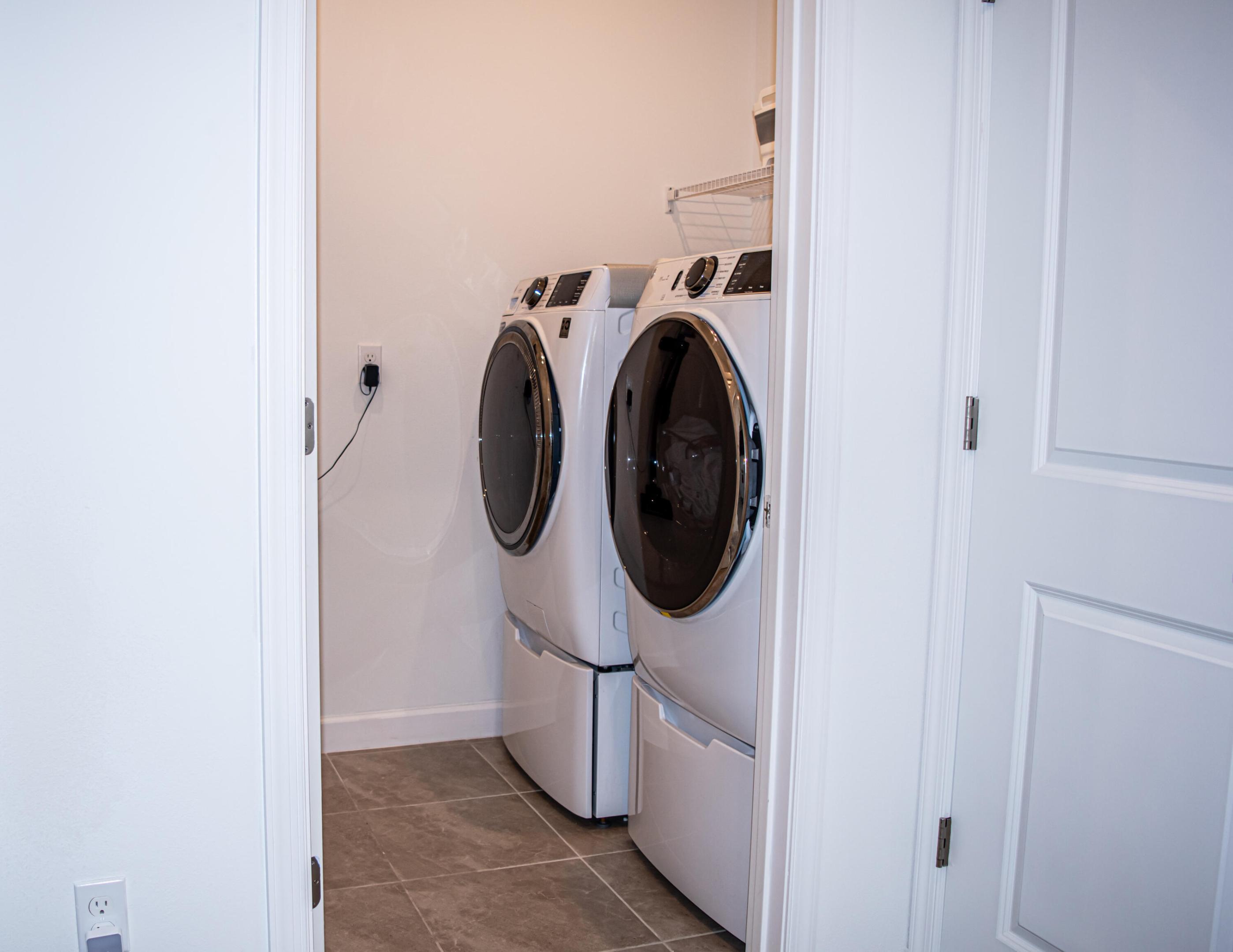 Laundry area featuring tile flooring, white-finish cabinetry, and wire shelving