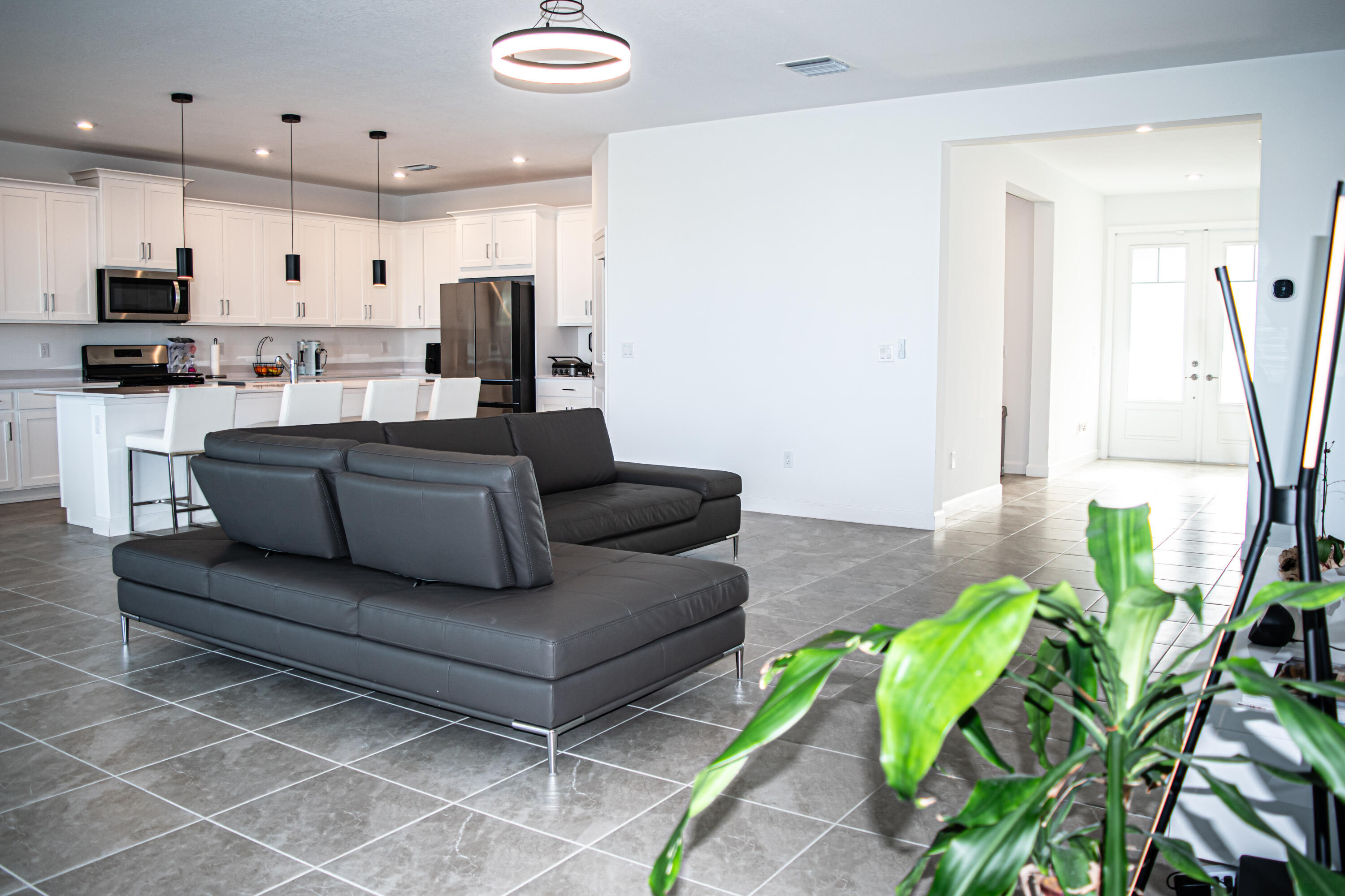 Open-concept kitchen featuring white shaker-style cabinetry, quartz countertops, a kitchen island, recessed lighting, and large-format tile flooring