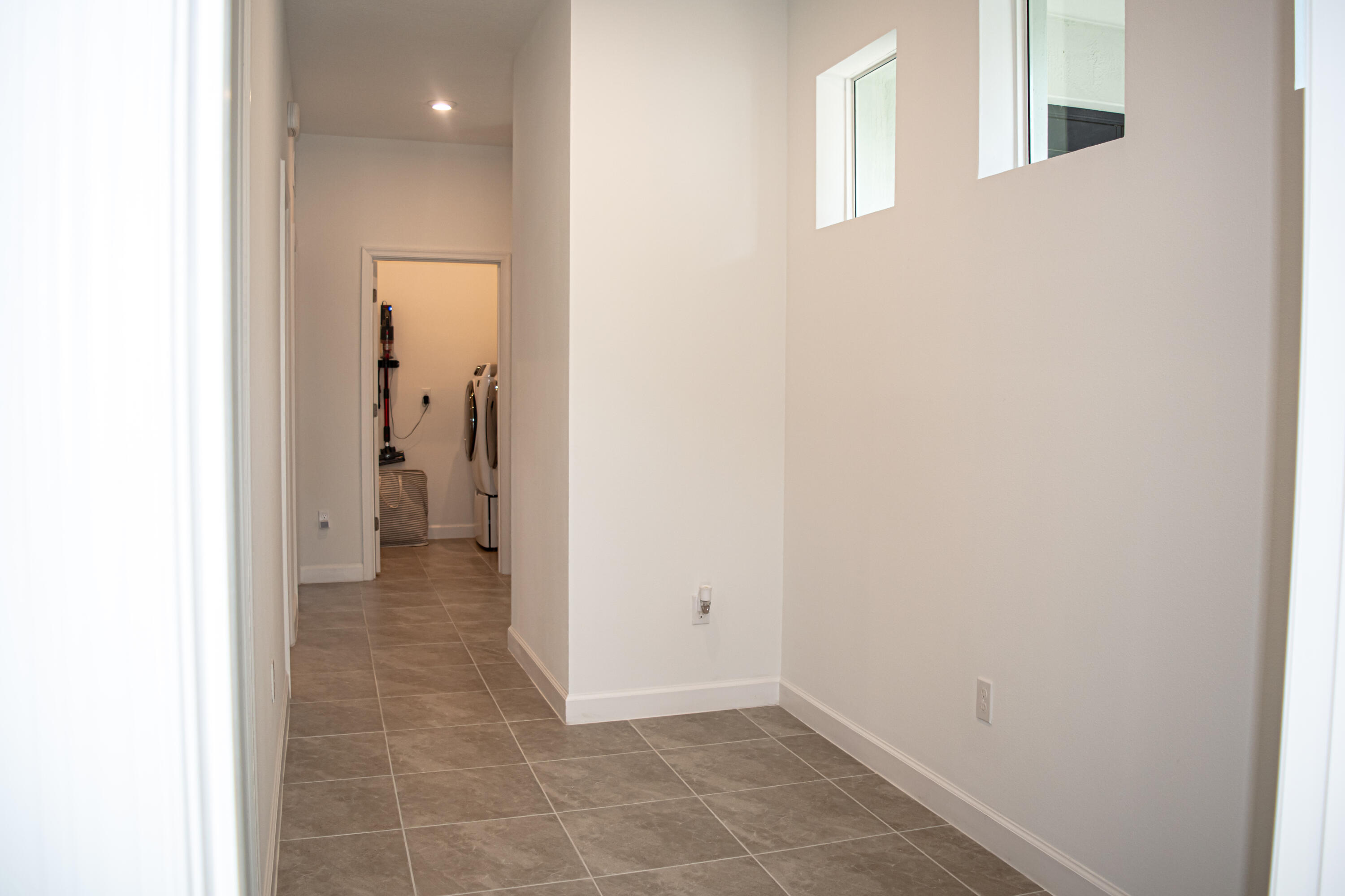Neutral-toned ceramic tile flooring, high-placed square windows, and recessed lighting