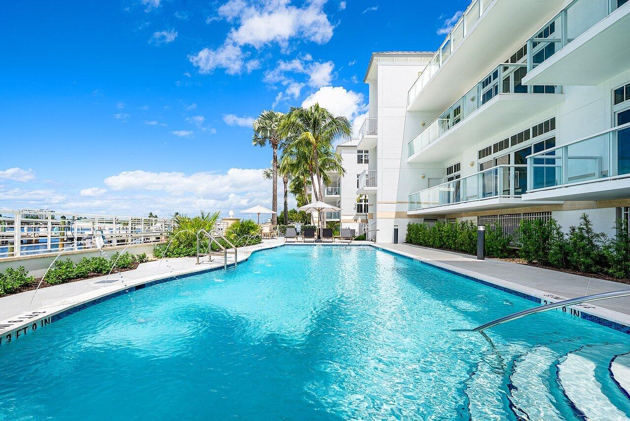 Swimming pool with built-in stairs, metal handrails, perimeter tile detailing, stone-paver decking, and glass-paneled balconies