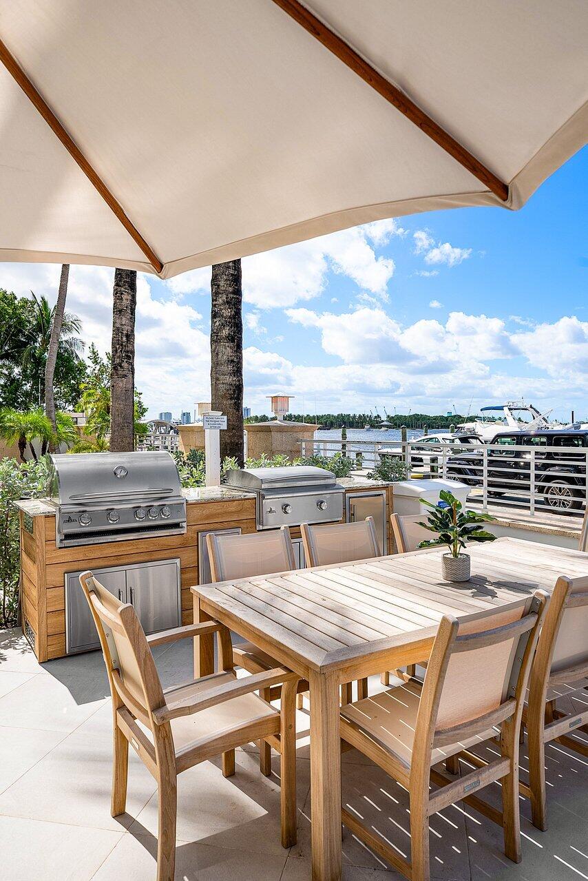 Outdoor kitchen featuring stainless steel built-in grills, stone countertops, and wood-finish cabinetry, set on a tiled patio