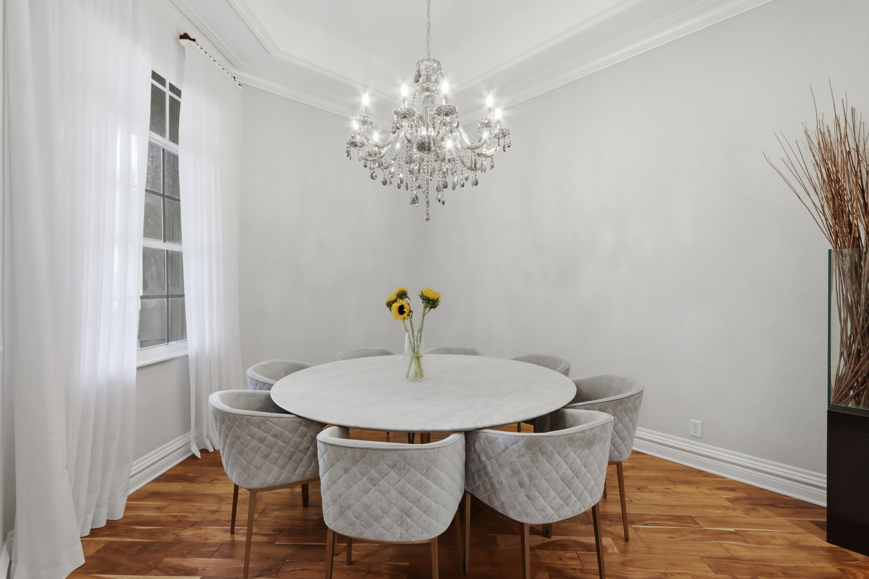 Tray ceiling featuring a crystal chandelier and wood-finish flooring