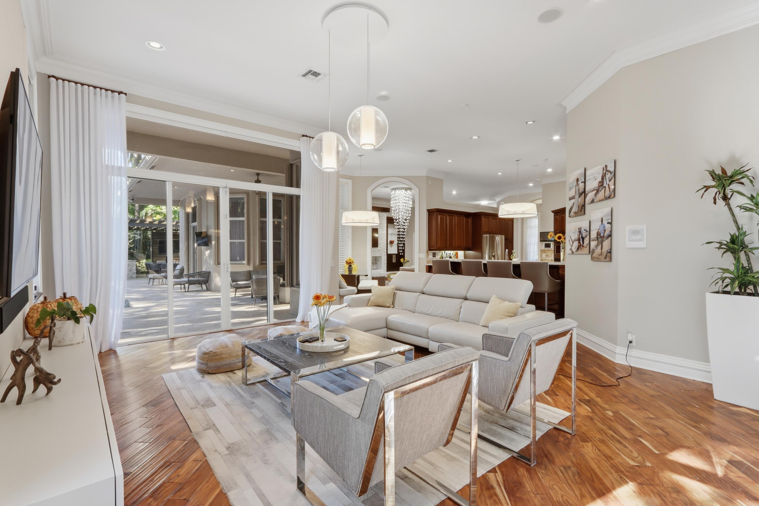 Open-concept living space featuring wood-finish flooring, recessed lighting, multi-pendant light fixtures, and expansive glass sliding doors