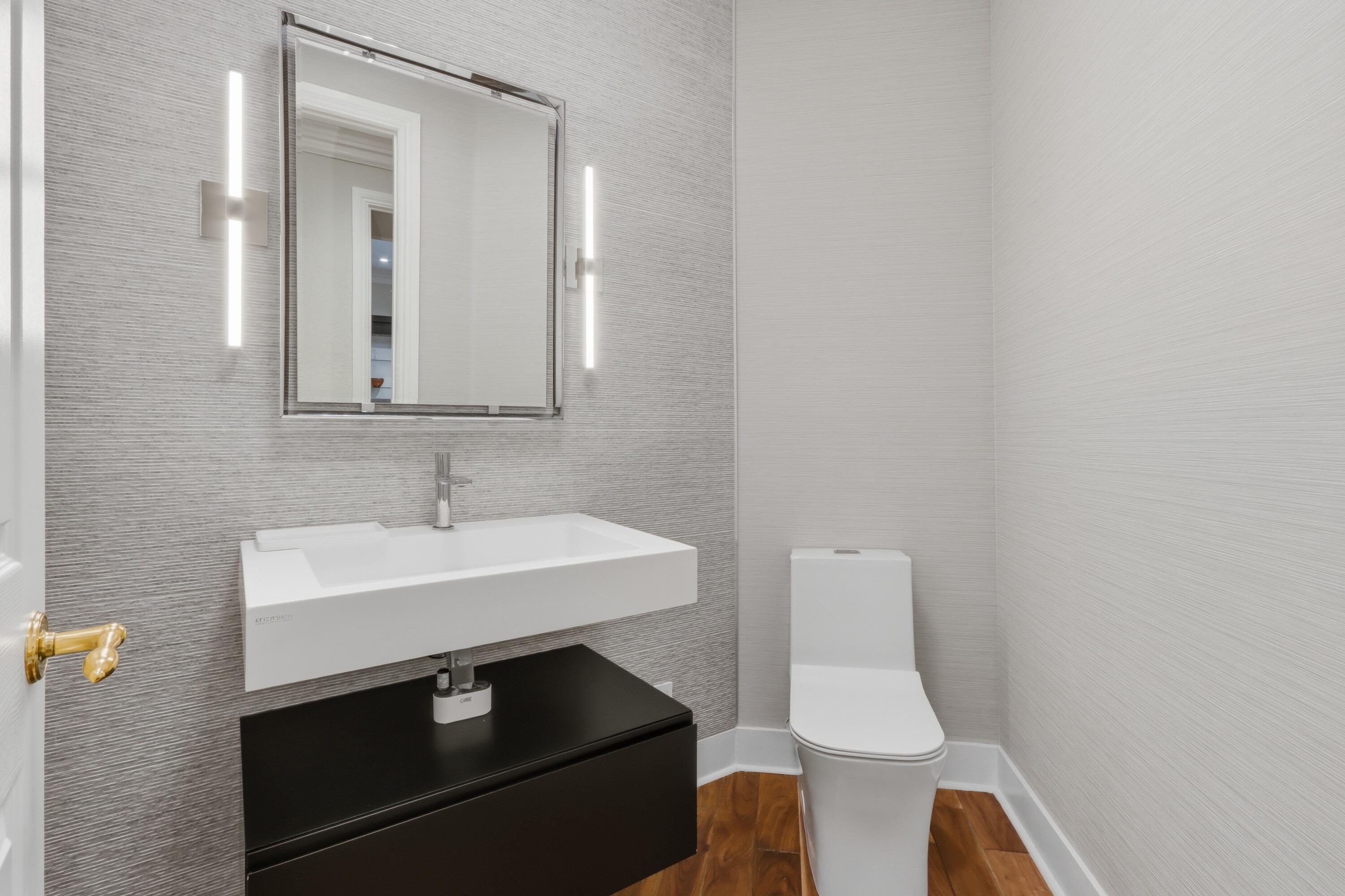 Wall-mounted vanity with a rectangular sink, dual vertical LED sconces, textured wall covering, and wood-finish flooring