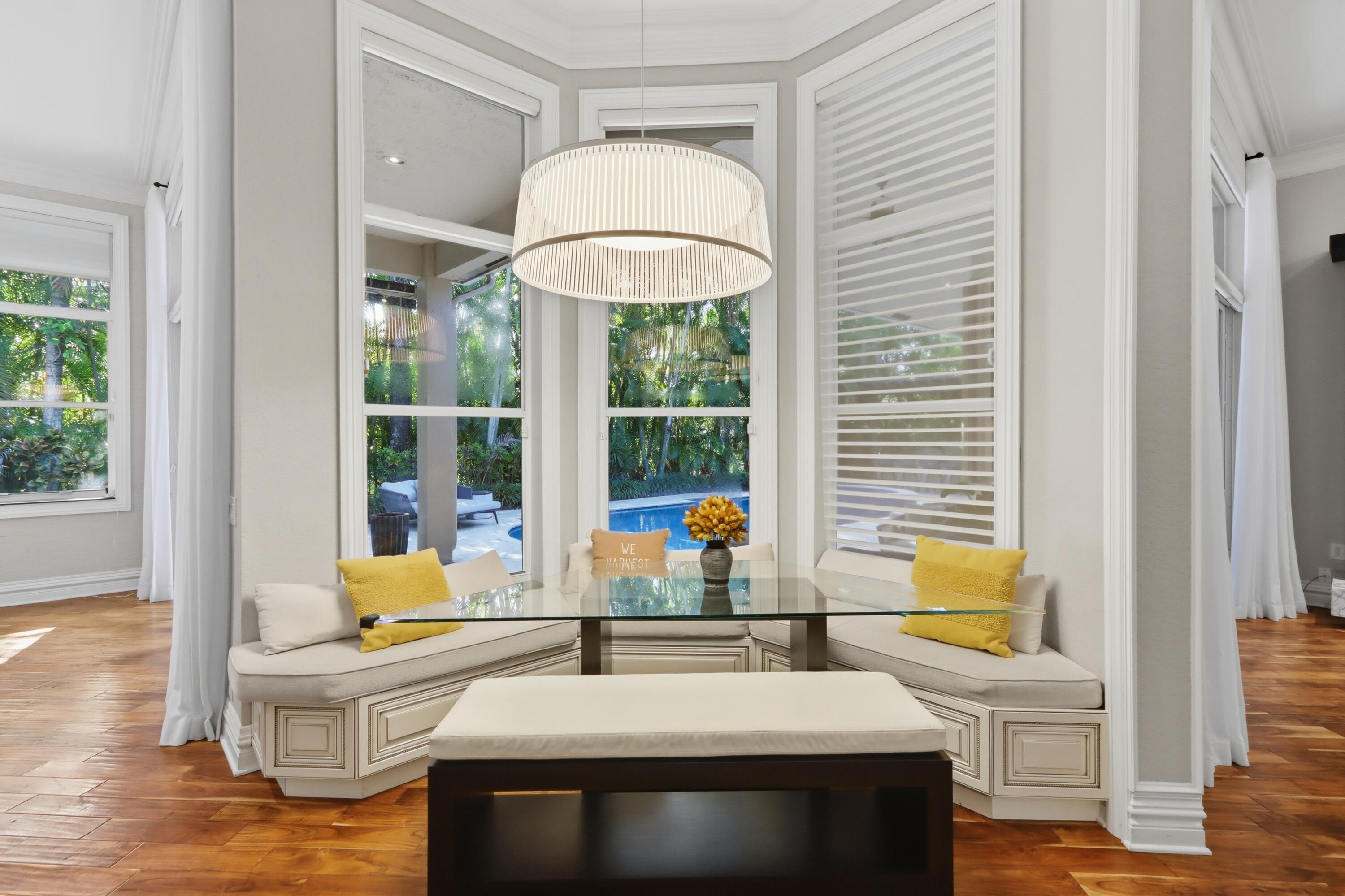 Bay window featuring built-in bench seating, wood-finish flooring, floor-to-ceiling windows, and a drum-style pendant light fixture