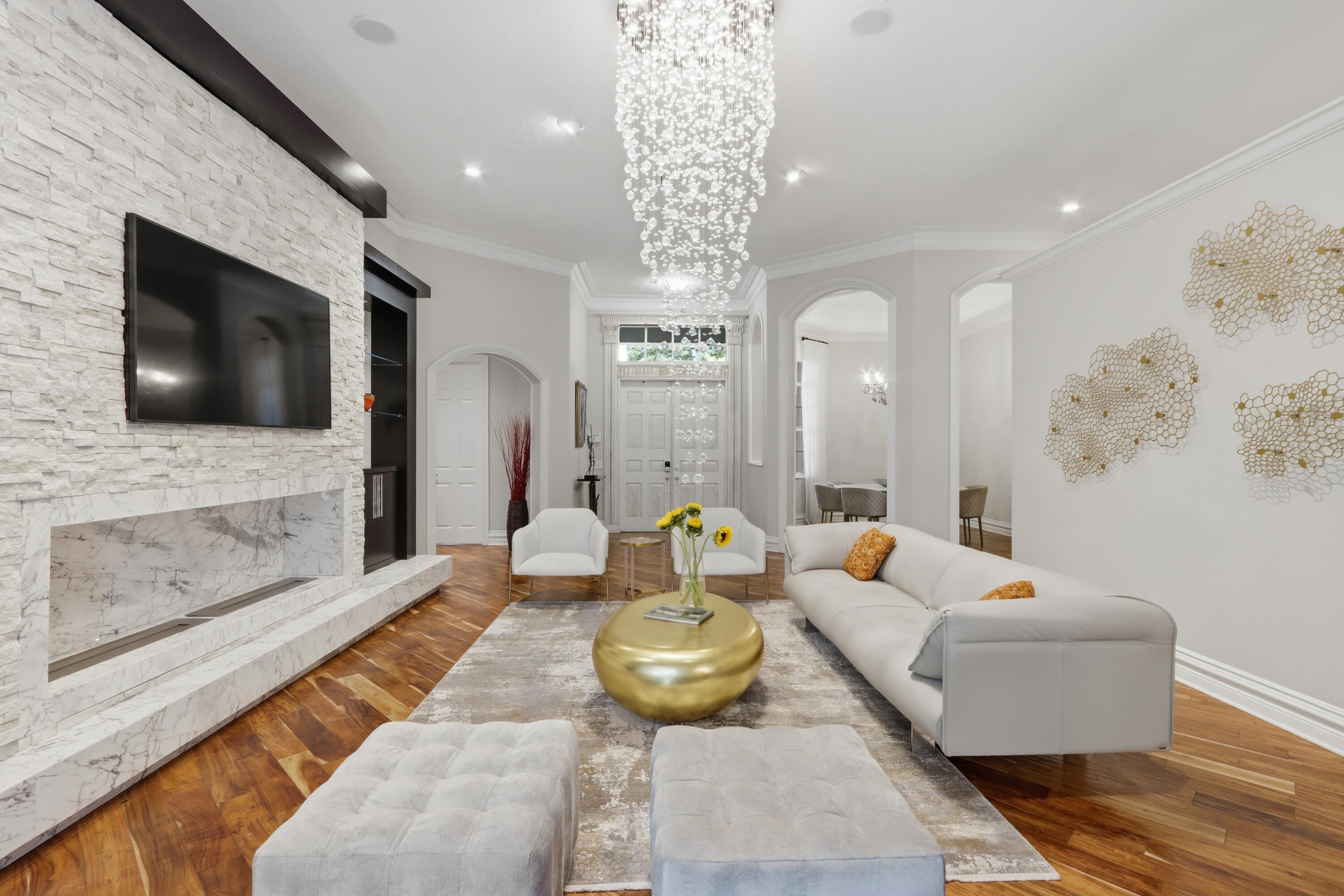 Formal living area featuring wood-finish flooring, a floor-to-ceiling stone-clad fireplace, a tiered crystal chandelier, and arched doorways