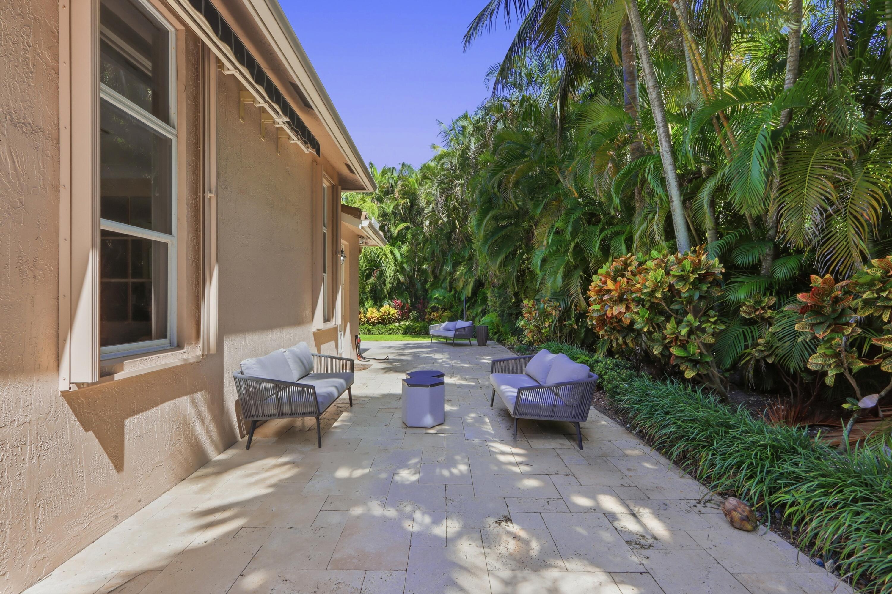 Paved stone patio featuring retractable awning and dense, mature tropical landscaping