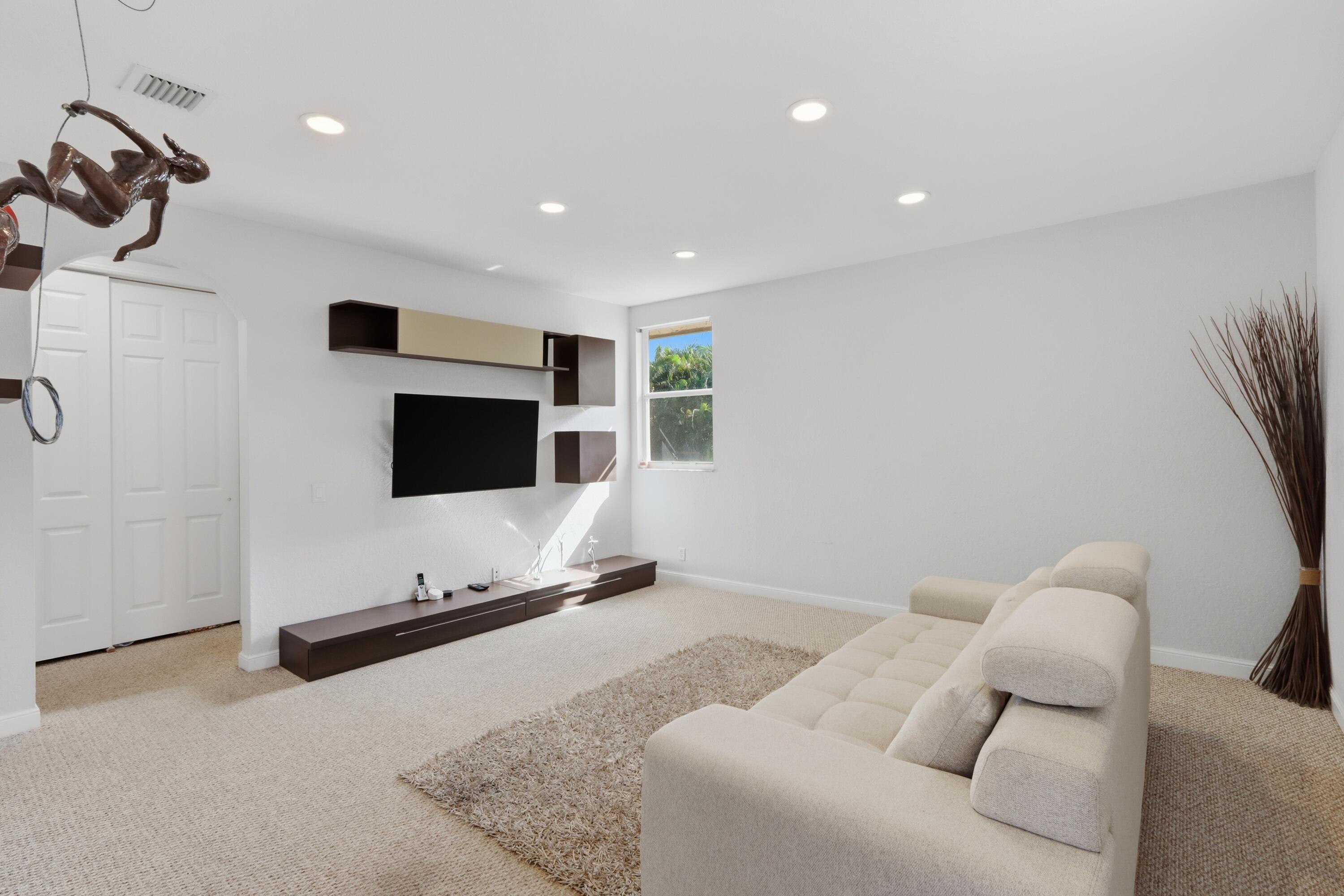 Recessed ceiling lighting, wall-mounted cabinetry, custom media shelving, and dual-panel closet doors