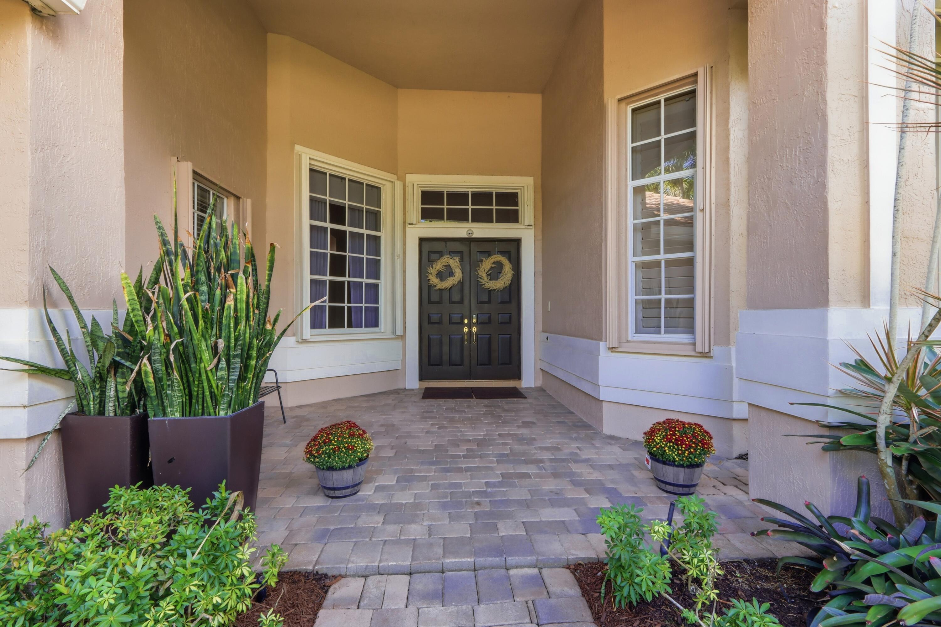 Covered entryway featuring a paver stone porch, double front doors, and a transom window Covered entryway featuring a paver stone porch, double front doors, and a transom window