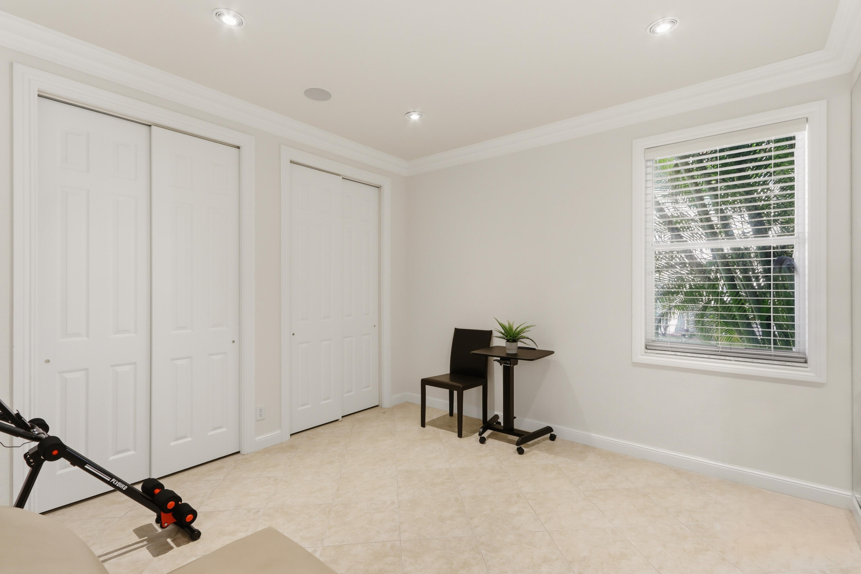 Neutral-toned tile flooring, recessed ceiling lighting, crown molding, and two sets of double-panel closet doors
