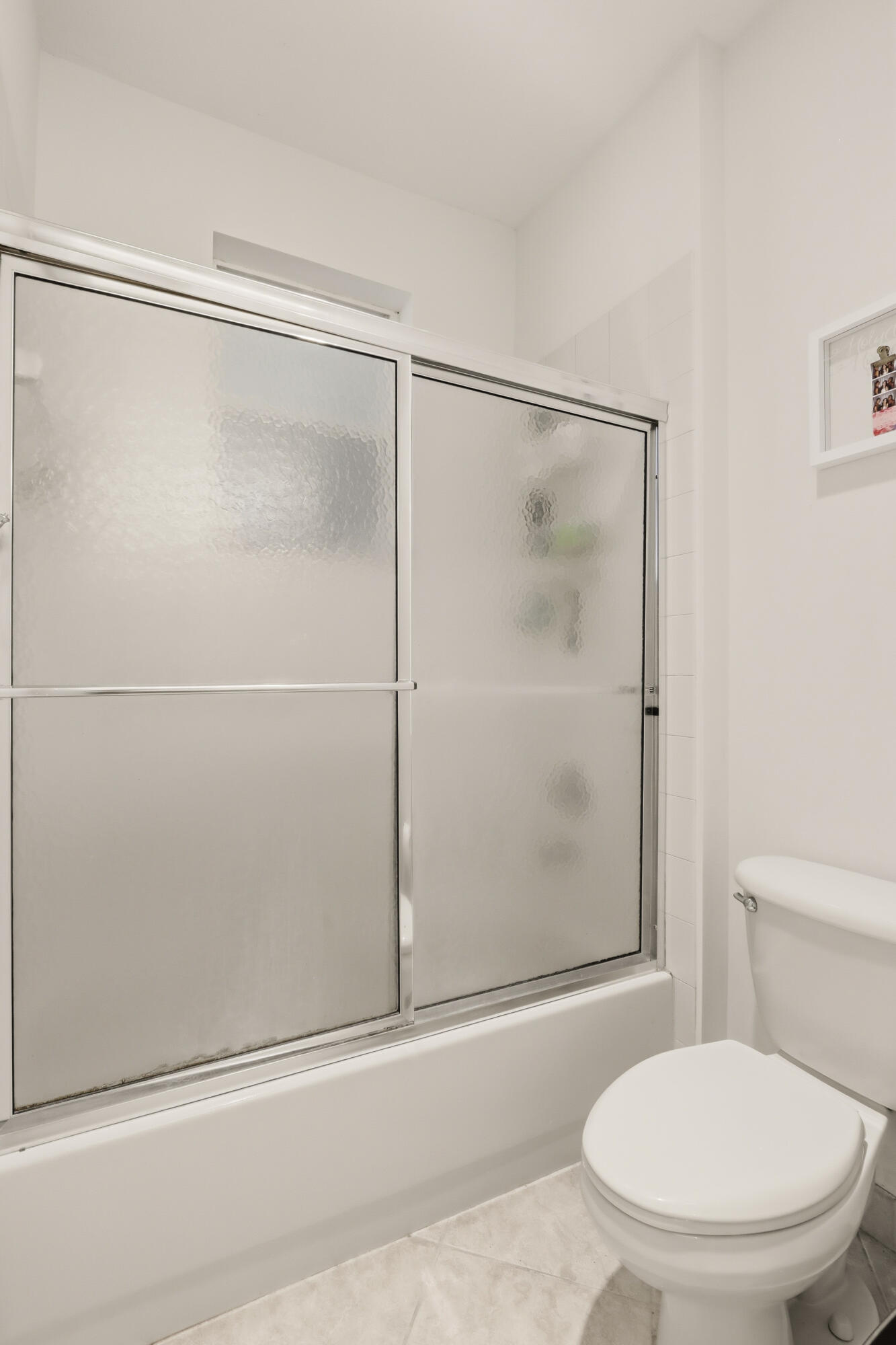 Shower enclosure with chrome-finished sliding glass doors, and a standard-height porcelain toilet