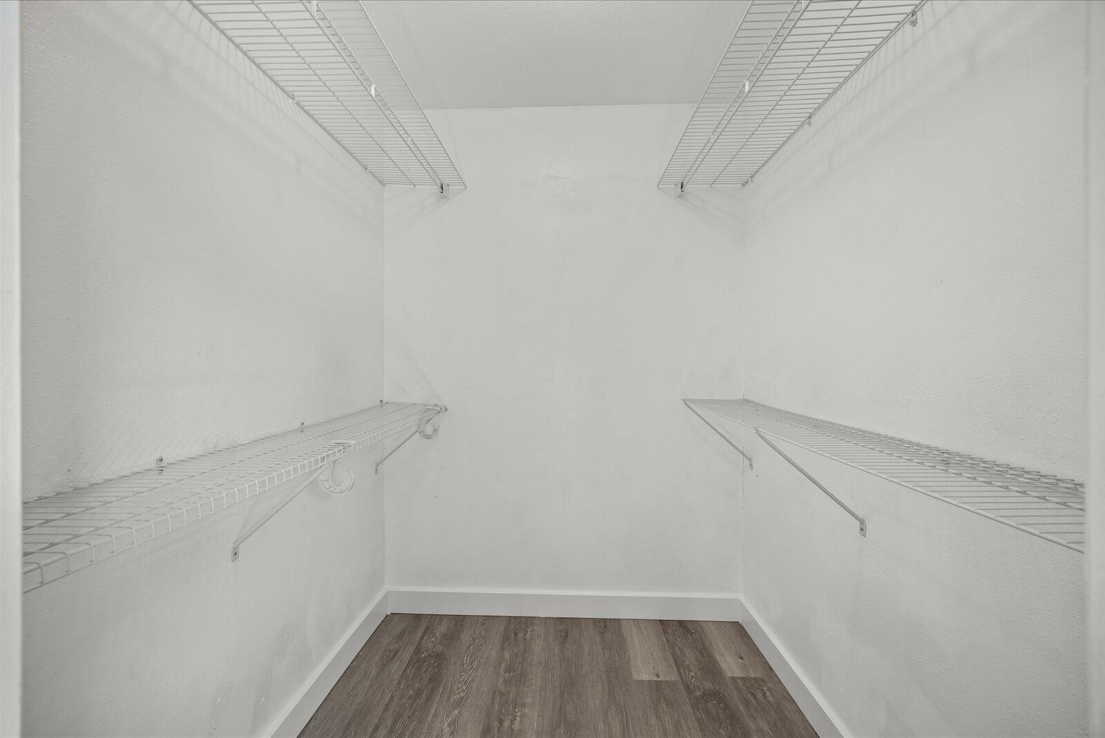 Walk-in closet featuring dual-level white wire shelving and wood-finish flooring