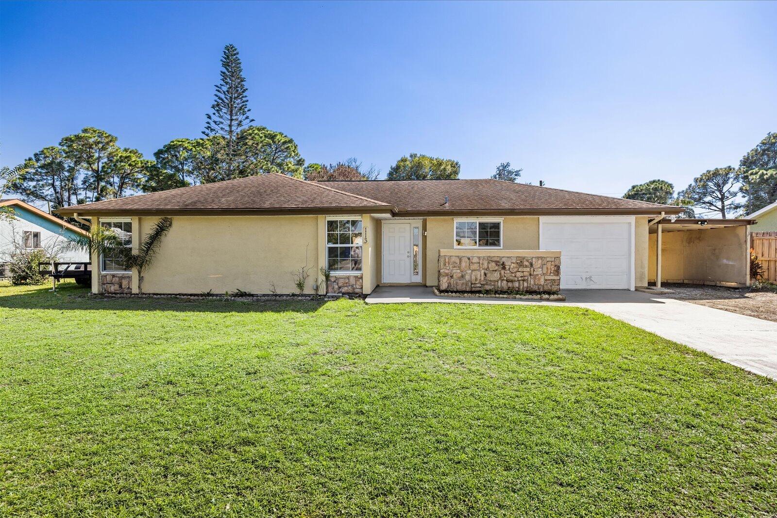Single-story residence featuring a stone-veneer accent wall, an attached garage, a side carport, and a concrete driveway