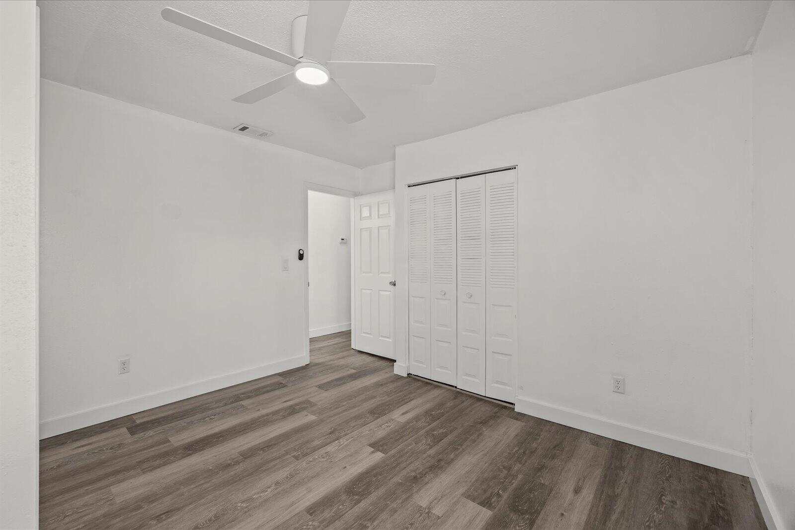 Neutral interior featuring wood-finish flooring, a contemporary ceiling fan with integrated lighting, and a closet with louvered doors