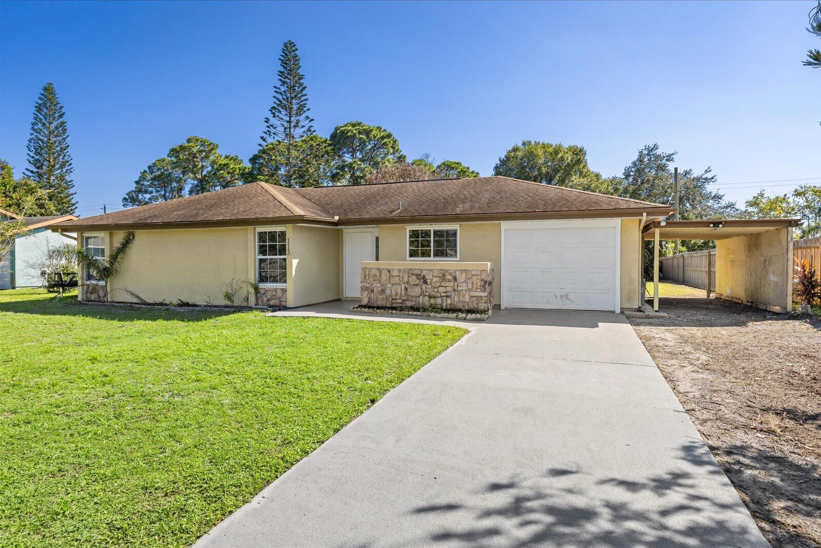Single-story residence featuring a stone-clad facade, attached one-car garage, covered carport, and concrete driveway