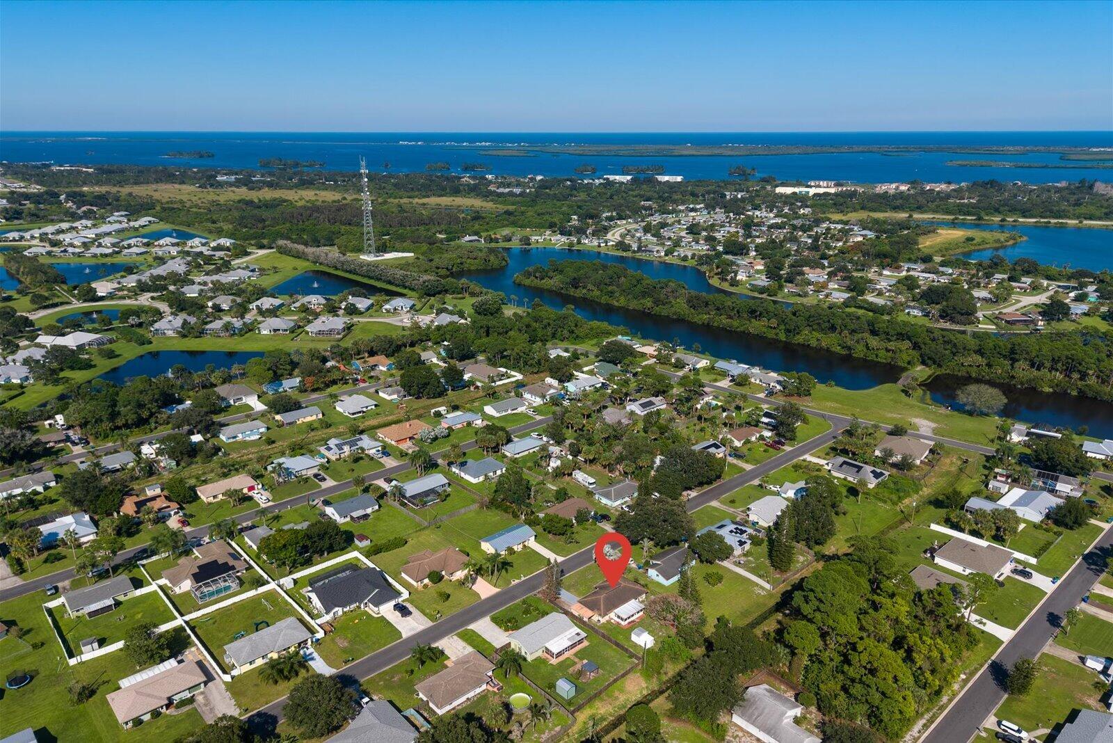 Aerial perspective showcasing a residential lot situated within a waterfront community featuring canal access and mature greenery