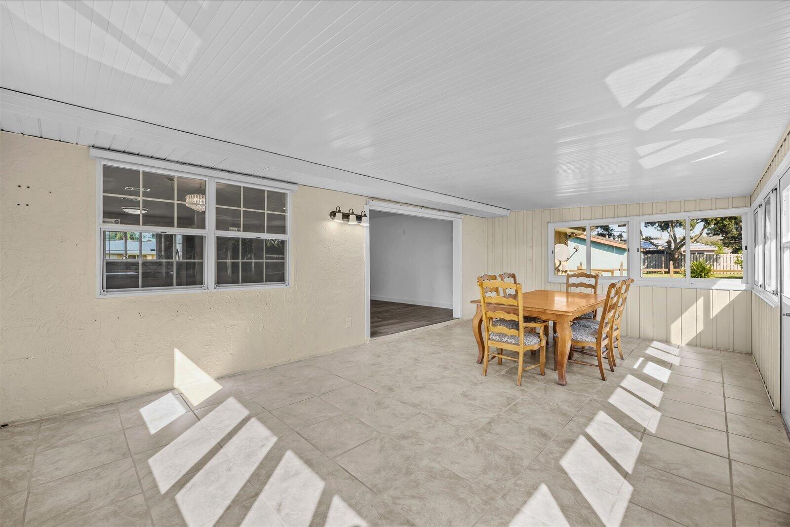 Enclosed patio featuring large-format tile flooring, a tongue-and-groove ceiling, multi-pane windows, and wall-mounted light fixtures