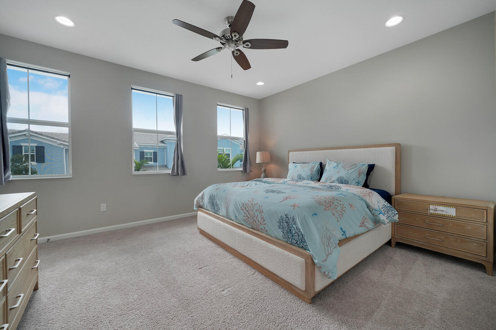Neutral-toned interior featuring recessed lighting, a multi-blade ceiling fan, and three windows with dual-pane frames
