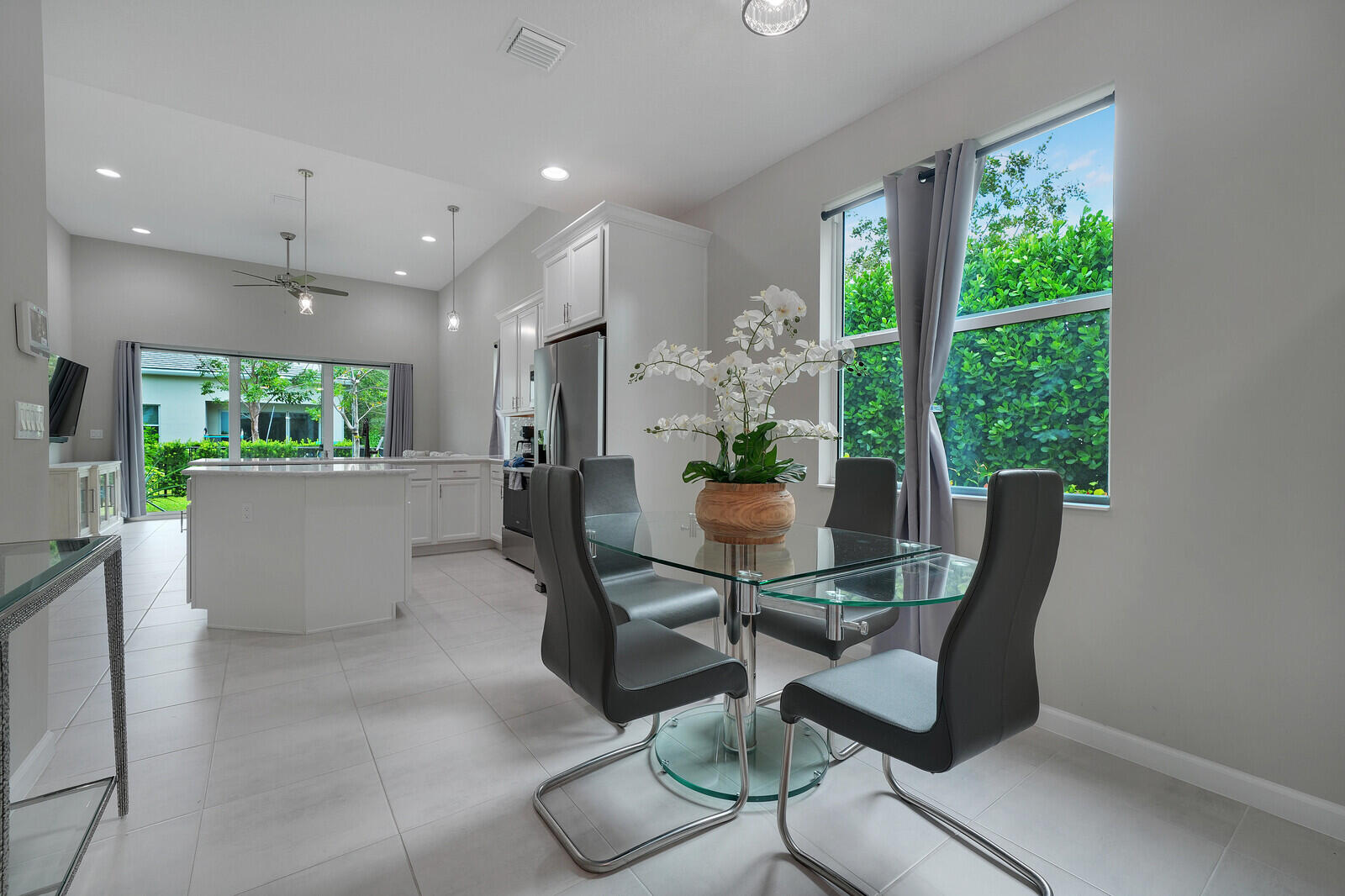 Open-concept kitchen featuring white cabinetry, a center island with countertop seating, large-format tile flooring, and recessed lighting
