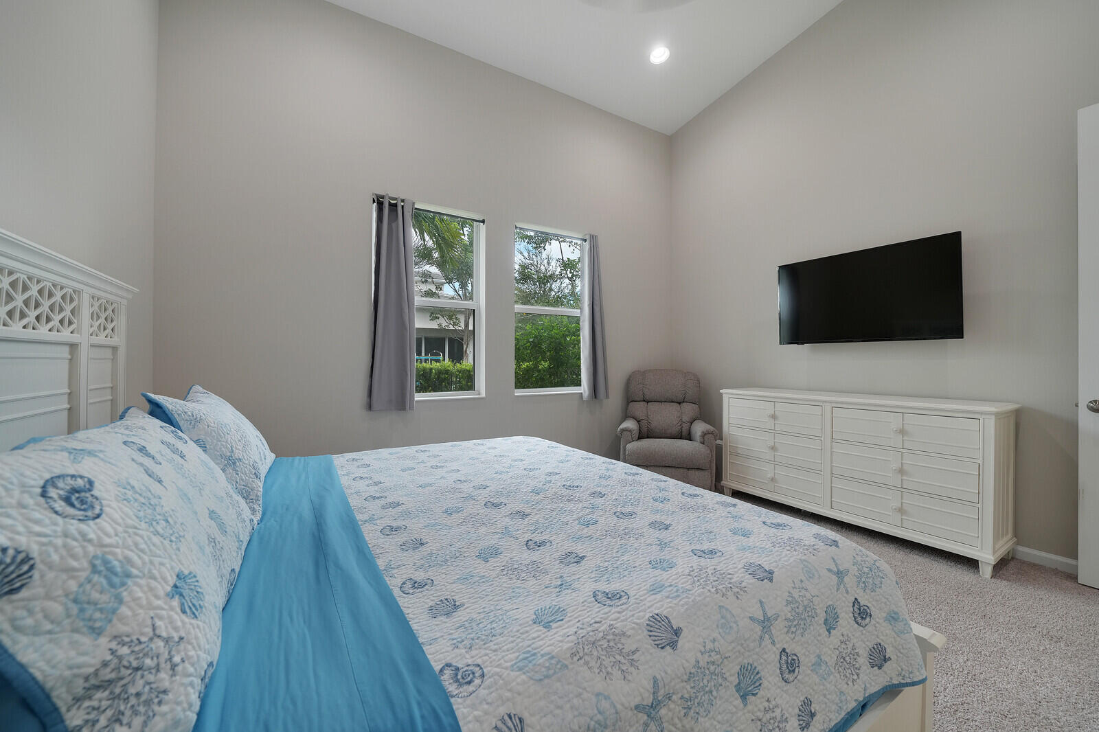 Vaulted ceilings, neutral wall tones, carpeted flooring, and dual windows with natural lighting