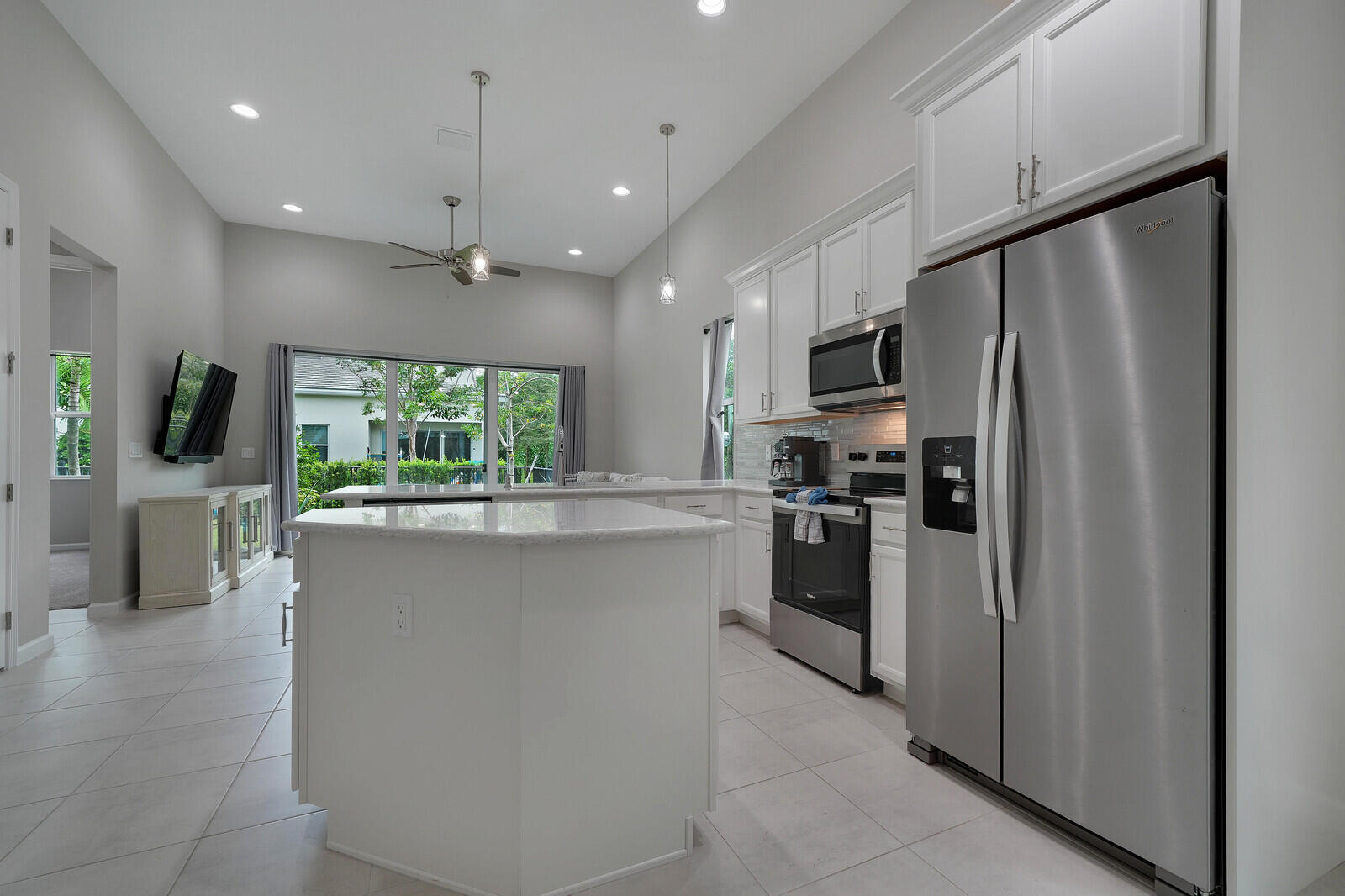Kitchen featuring white cabinetry, extended countertops perfect for functional living/cooking and entertaining, stainless steel appliances, a center island, and vaulted ceilings