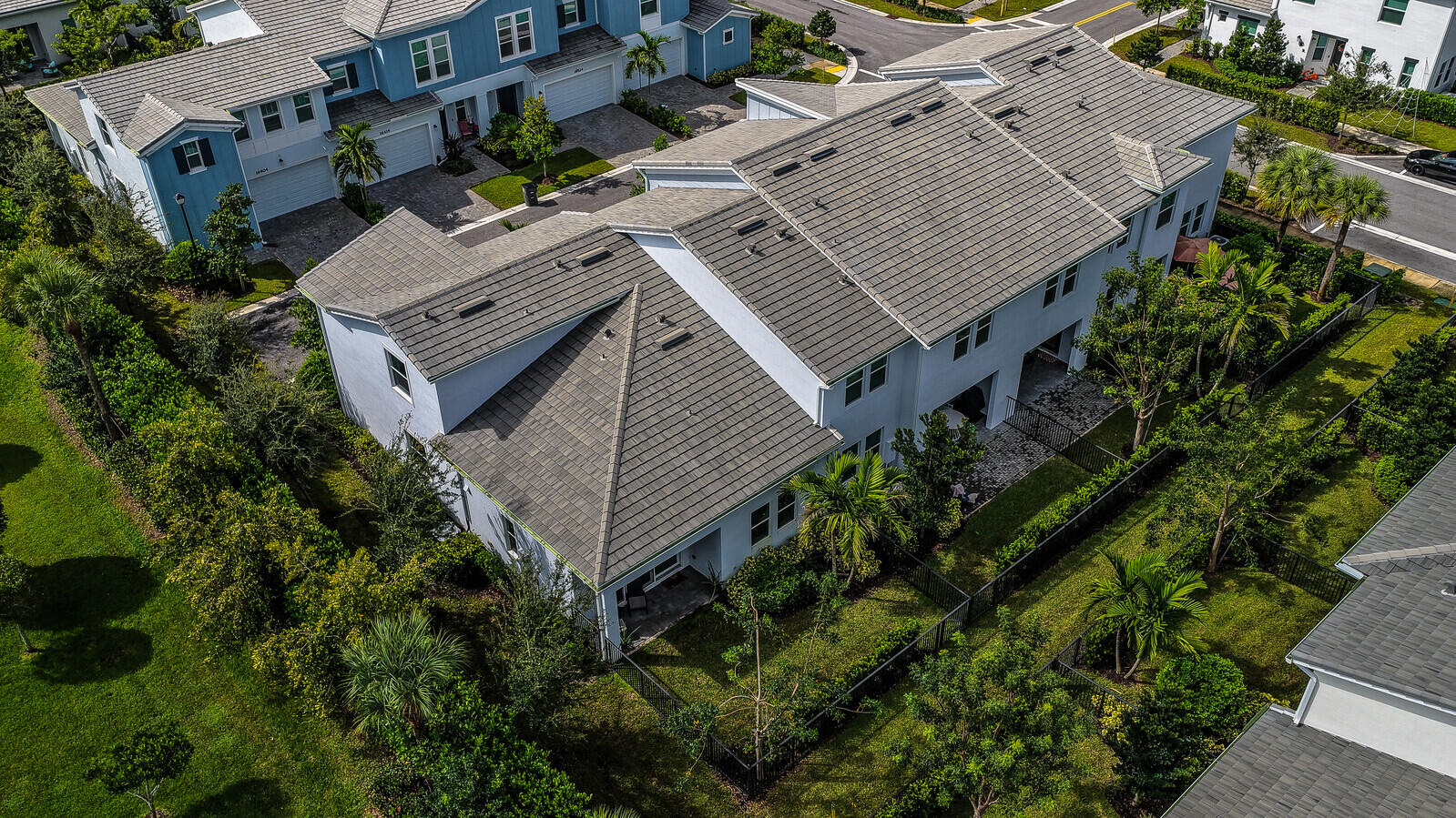 Multi-story residential structure featuring a multi-gabled concrete tile roof, light-toned exterior finish, attached garage, covered rear patio, and fenced perimeter