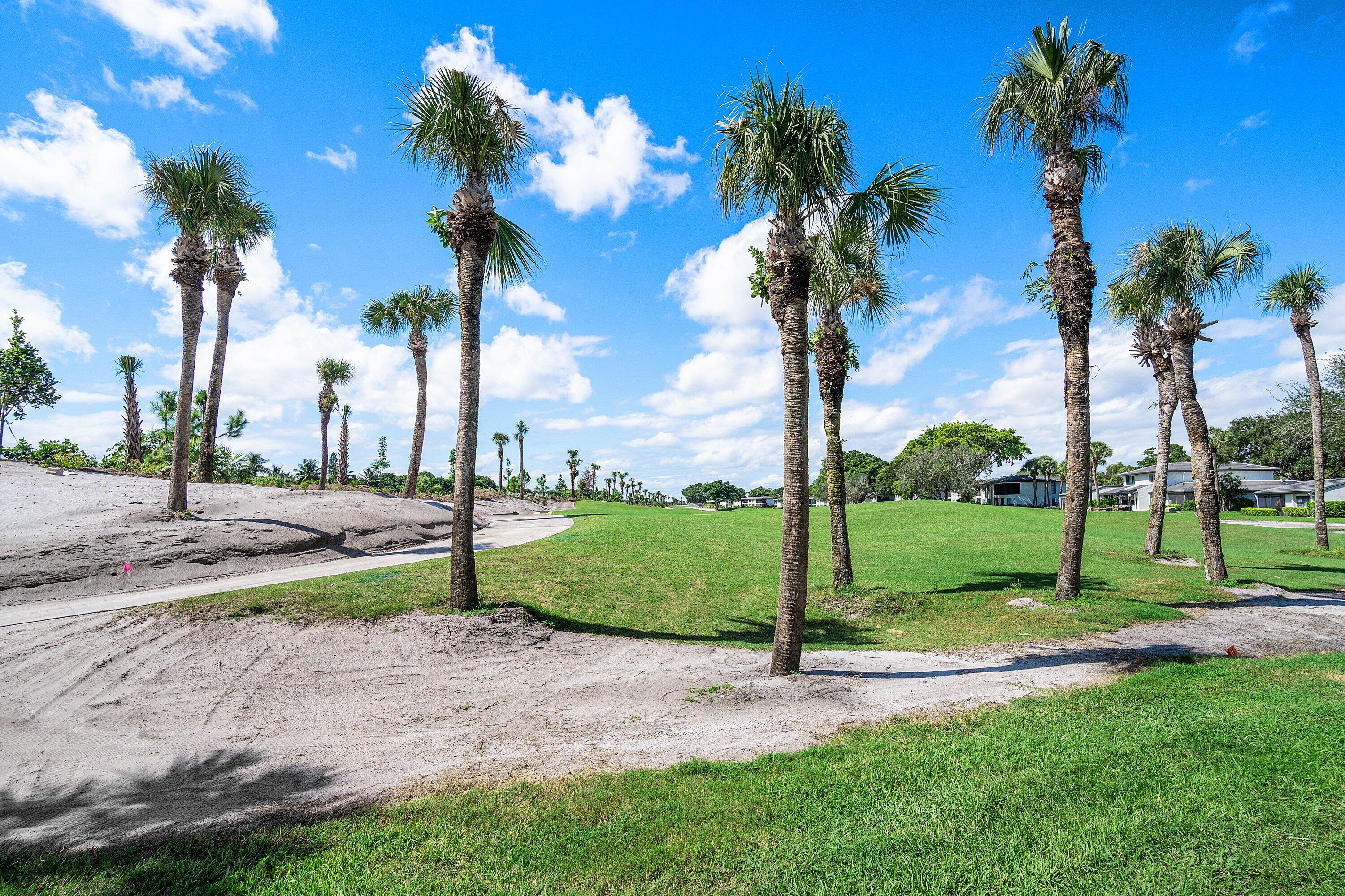 Extensive grounds featuring manicured turf, mature palm trees, and sand bunker elements