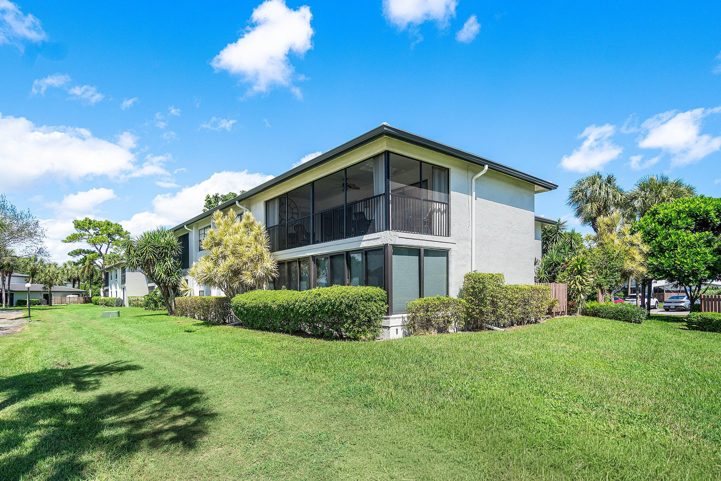 Multi-story exterior featuring light-toned masonry, tiered screened enclosures, and expansive surrounding green space
