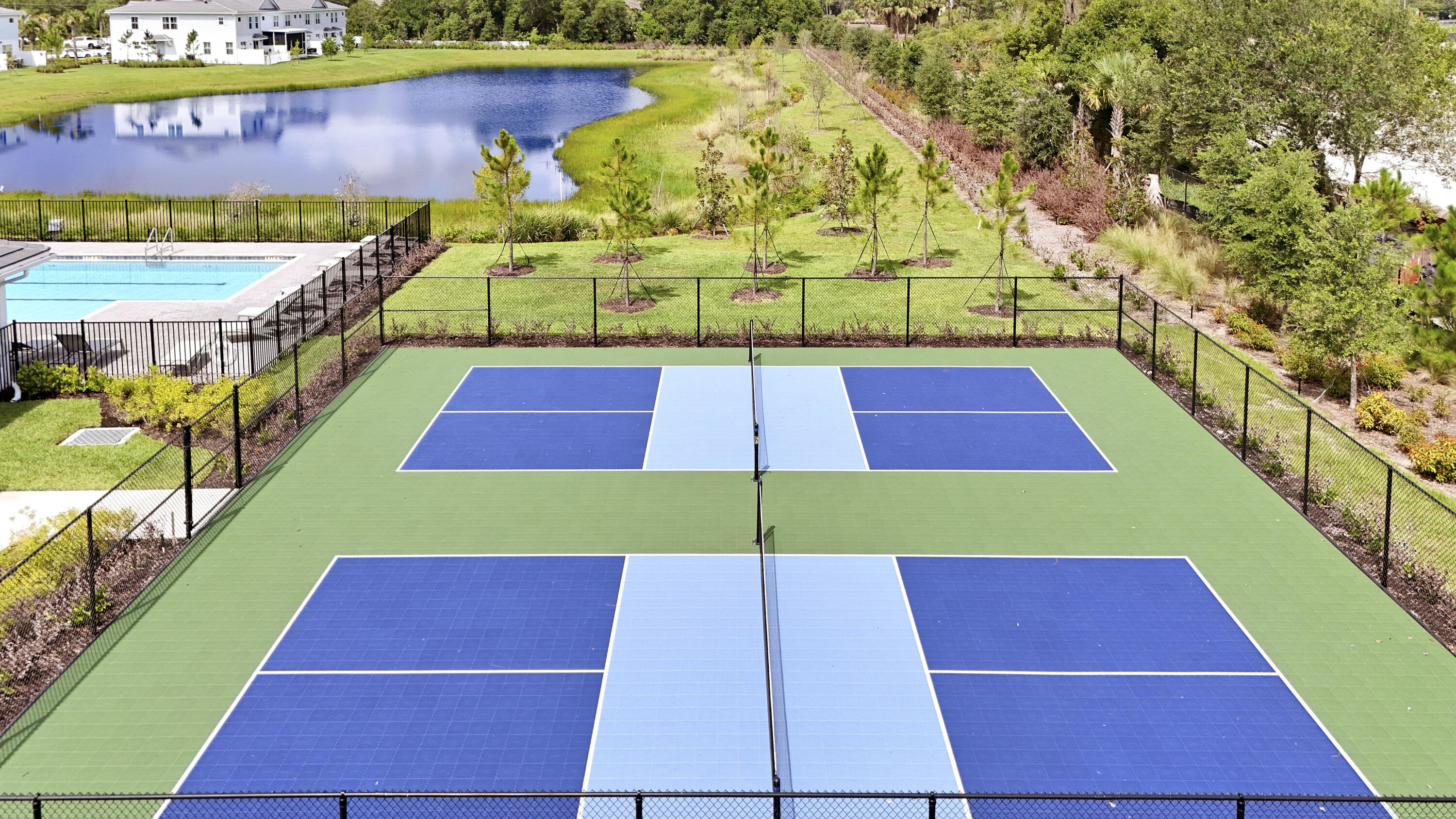 Multi-court athletic facility featuring blue and green surfaces, perimeter chain-link fencing, and an open-air layout.