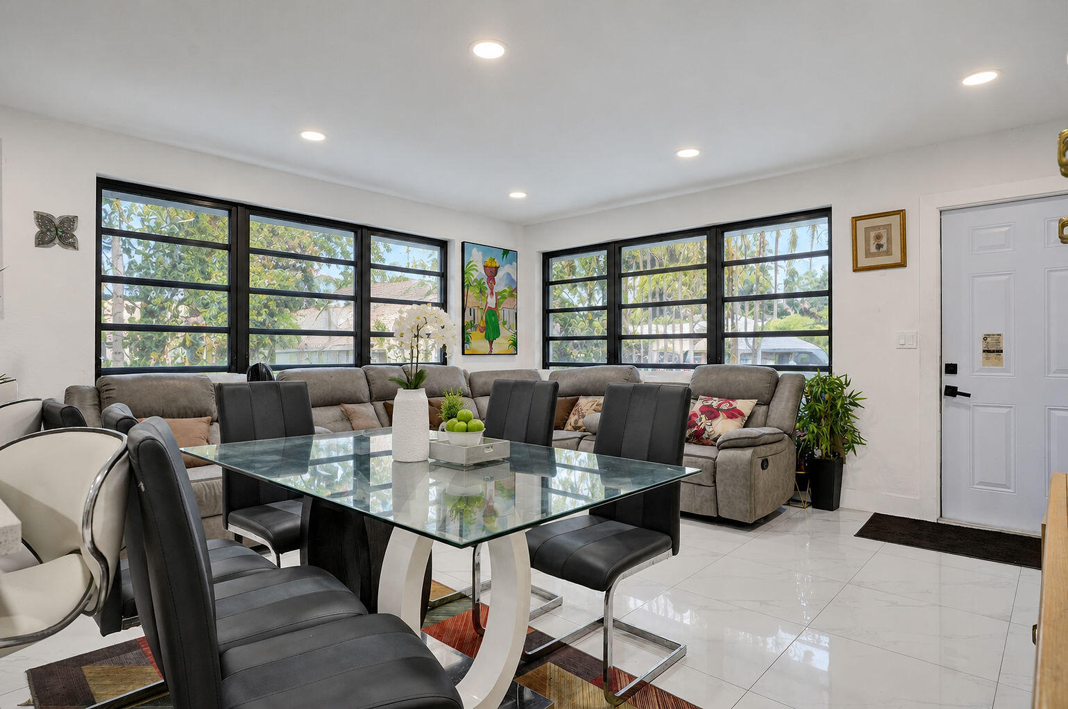 Large-format windows with black frames, recessed ceiling lighting, and polished stone-finish flooring