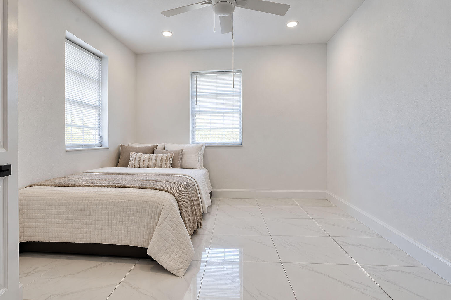 Neutral-toned interior featuring large-format tile flooring, recessed lighting, and a white ceiling fan with integrated light