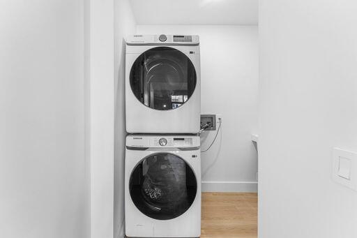 Stacked front-load laundry appliances with wood-finish flooring