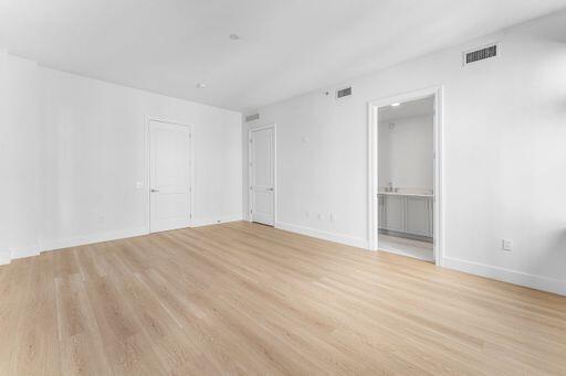 Interior space featuring light-toned wood-finish flooring, two solid-core doors, and crisp white wall finishes Interior space featuring light-toned wood-finish flooring, two solid-core doors, and crisp white wall finishes