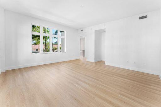 Open-concept living space featuring wood-finish flooring, high ceilings, and expansive multi-pane windows
