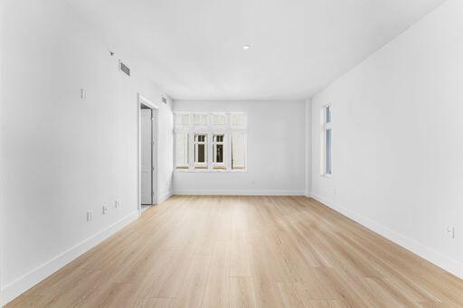 Open-concept room featuring light wood-finish flooring, white walls, and multiple multi-pane windows