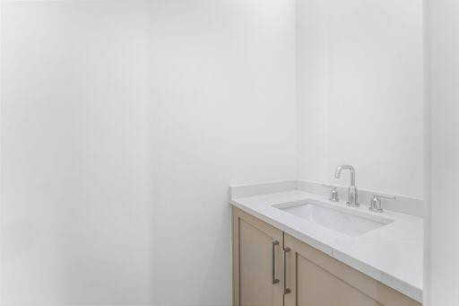 Vanity featuring wood-finish cabinetry, a white countertop, an integrated rectangular sink, and a chrome widespread faucet