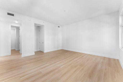 Interior space featuring light-toned wood-finish flooring, crisp white walls, and interior passage doors with brushed metal hardware