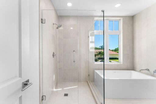 Frameless glass shower enclosure, deep soaking tub, polished chrome fixtures, and large-format tile surround