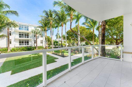 Covered balcony featuring large-format tile flooring and white structural framing with integrated glass panel railings