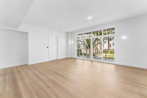 Interior space featuring wood-finish flooring, recessed ceiling lighting, wall-mounted light fixtures, and expansive floor-to-ceiling multi-panel windows with exterior metal railings