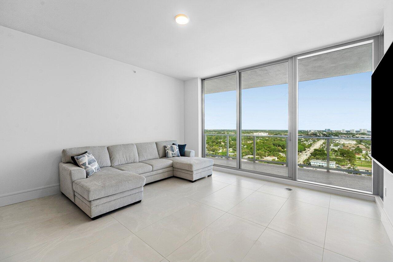 Floor-to-ceiling glass walls, expansive exterior balcony, large-format tile flooring, and flush-mount ceiling lighting
