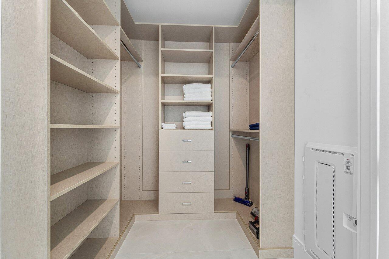 Custom walk-in closet featuring light-toned built-in shelving, four integrated storage drawers, and dual metal hanging rods