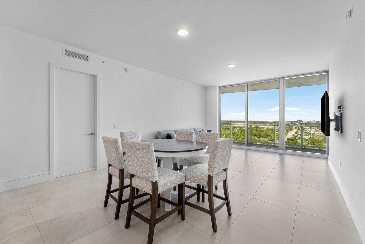 Open-concept interior featuring large-format tile flooring, recessed lighting, and floor-to-ceiling windows with balcony access