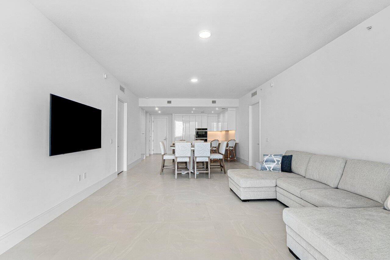 Open-concept area featuring light-toned tile flooring, recessed ceiling lighting, and crisp white walls