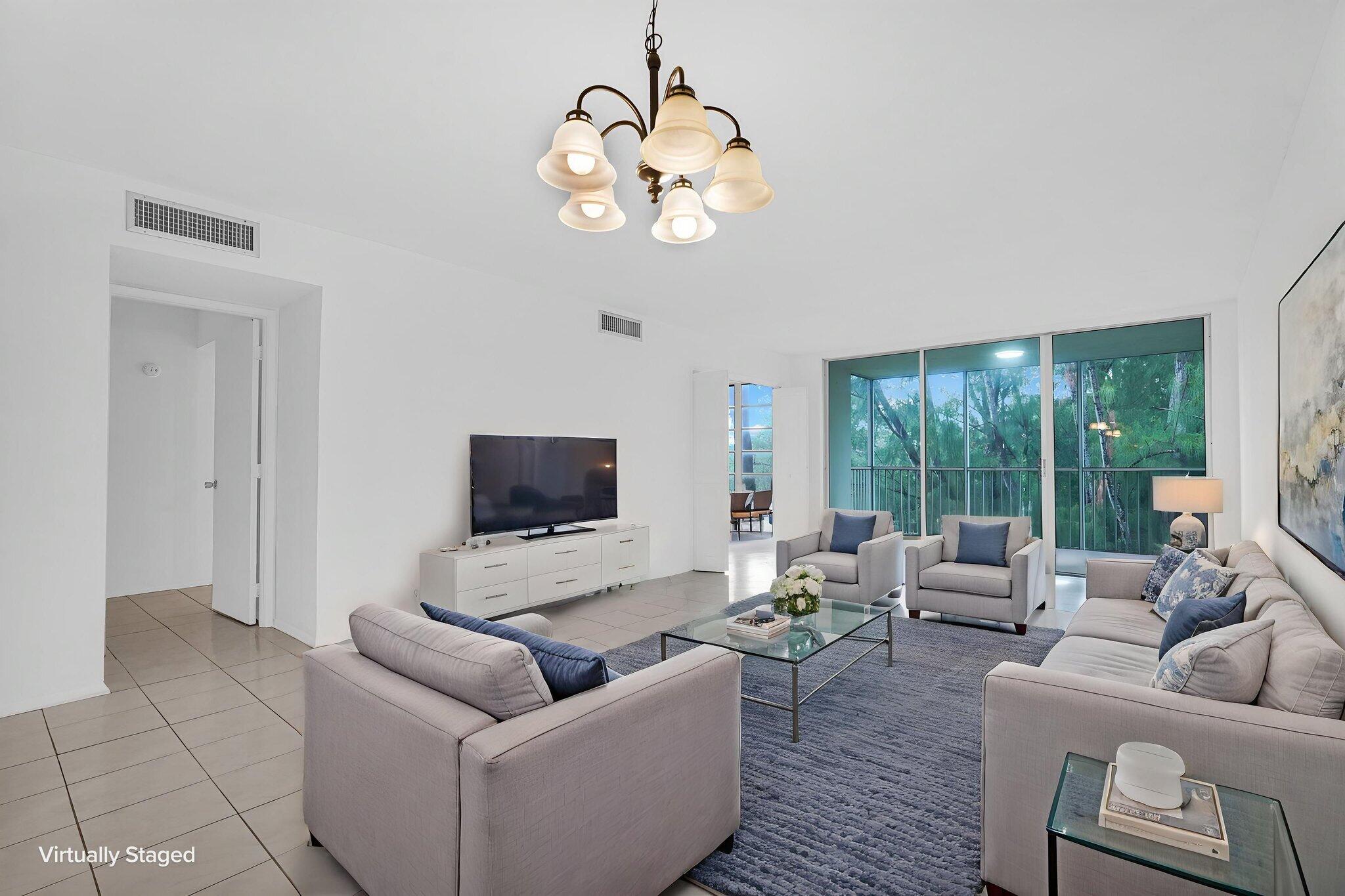 Living space featuring light-colored tile flooring, a five-arm multi-light chandelier, and large floor-to-ceiling glass sliding doors. Virtual Staged