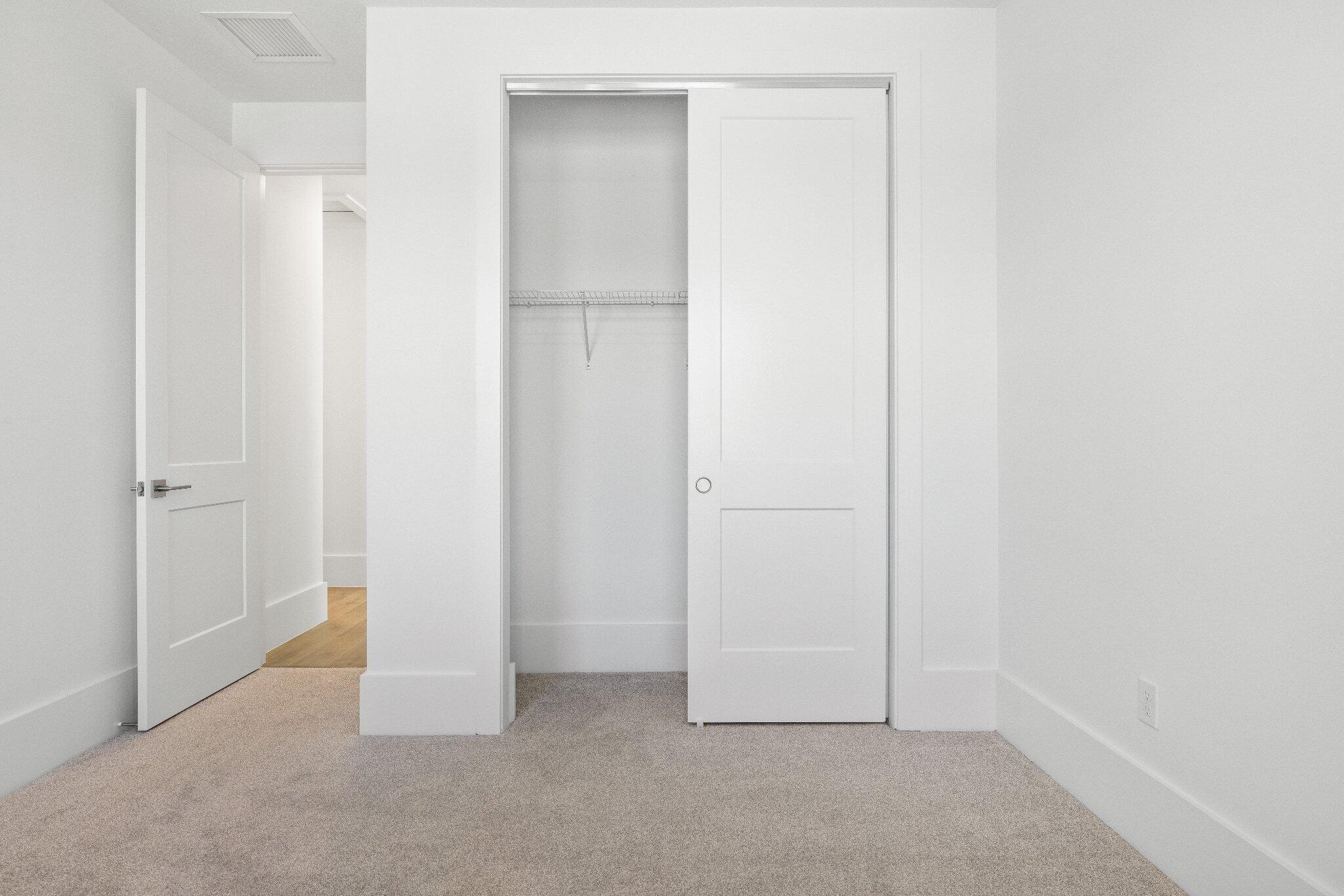 Interior room featuring neutral wall-to-wall carpeting, two-panel interior doors, and a built-in closet with integrated shelving