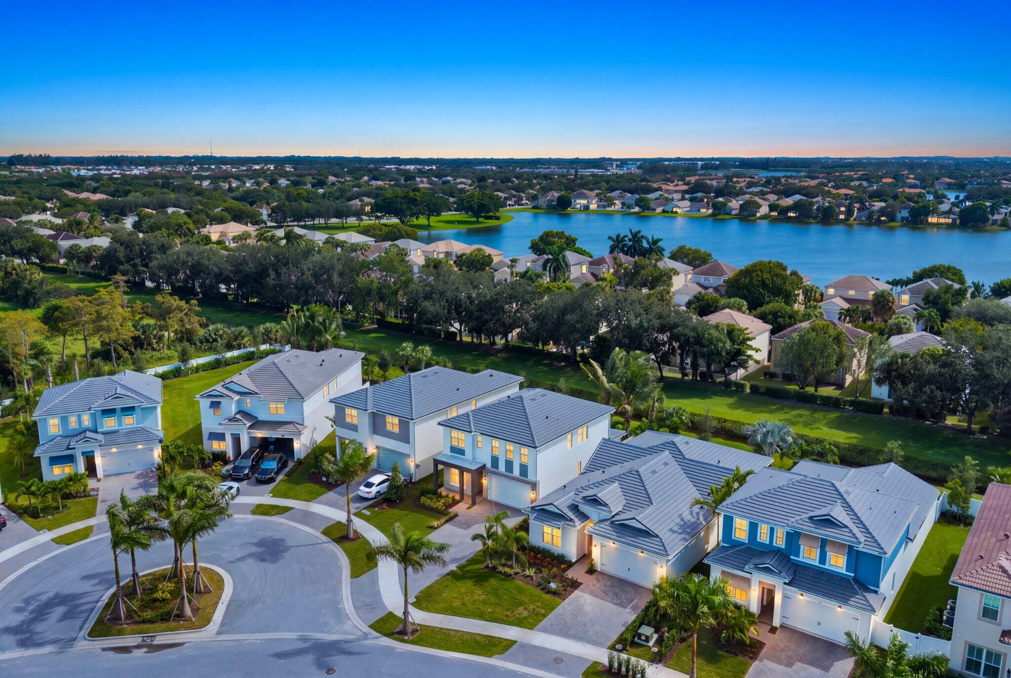 Aerial perspective of a suburban neighborhood featuring multi-story residences, paved cul-de-sac, tiled roofing, and extensive water frontage