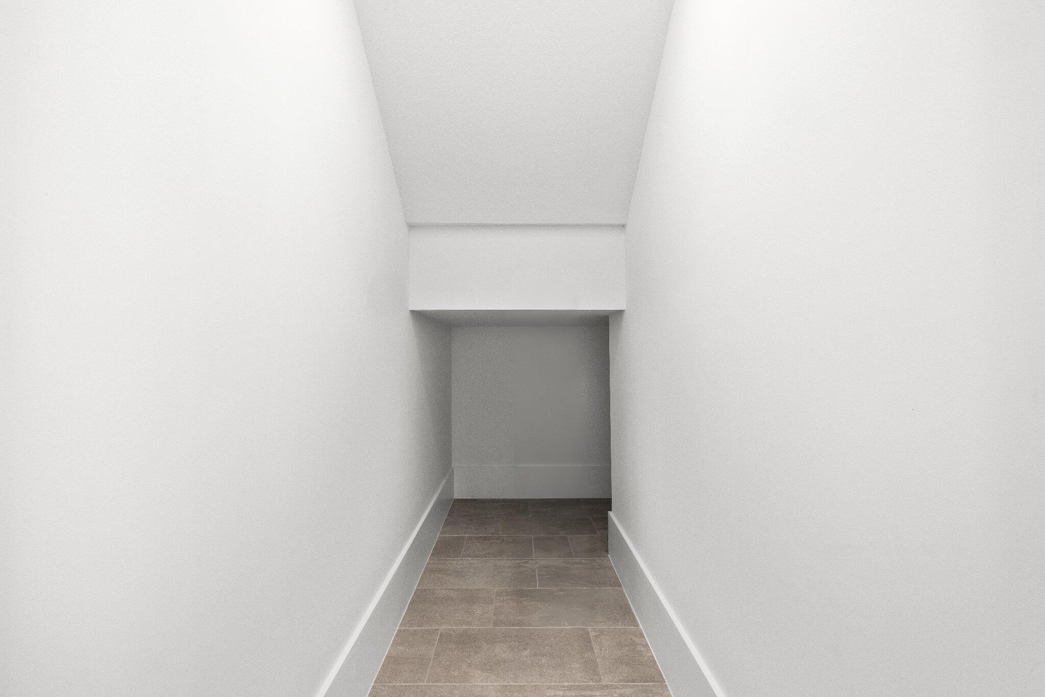 Enclosed storage area featuring neutral-toned tile flooring and smooth, white walls