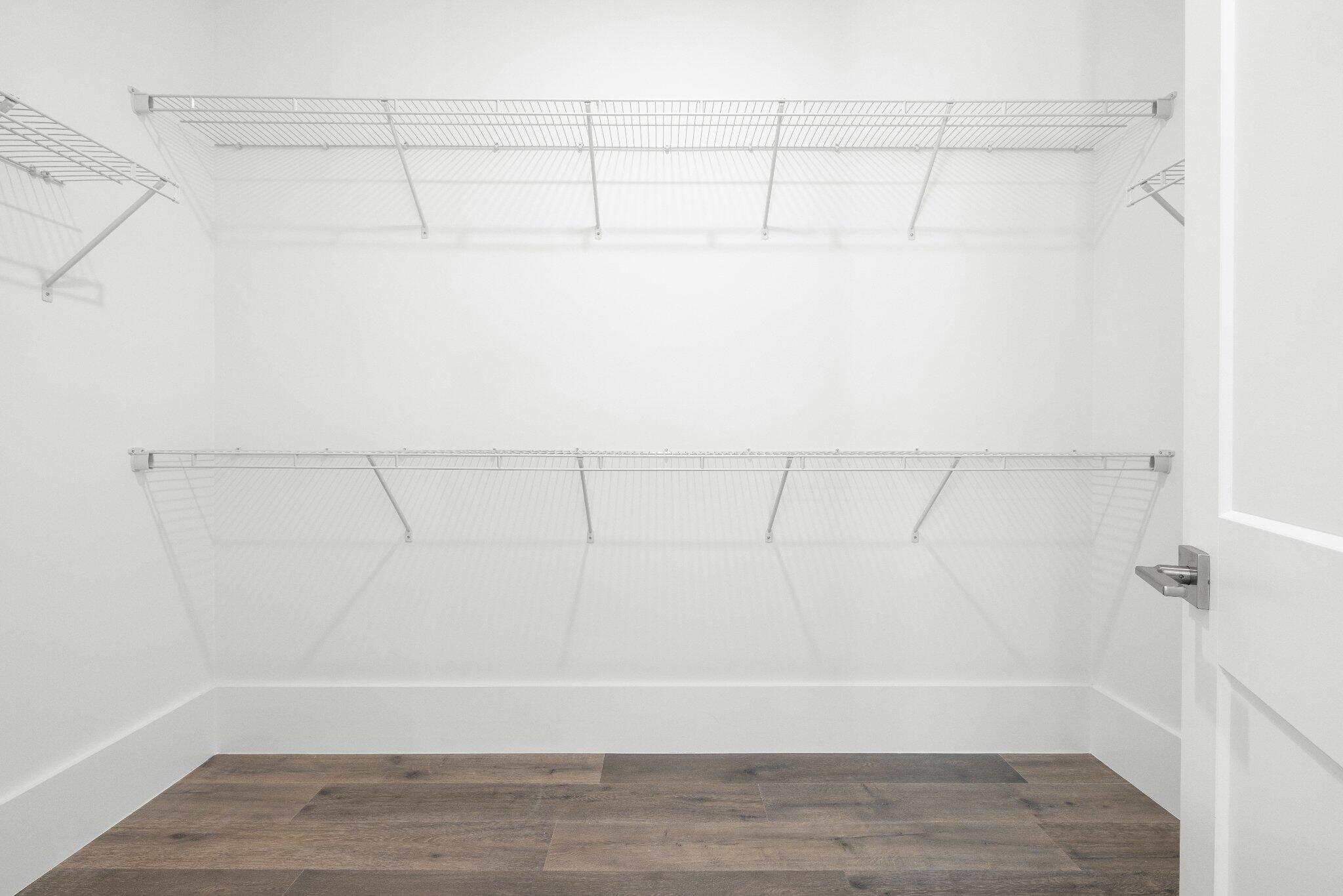 Storage space featuring dual-level wire shelving and wood-finish flooring