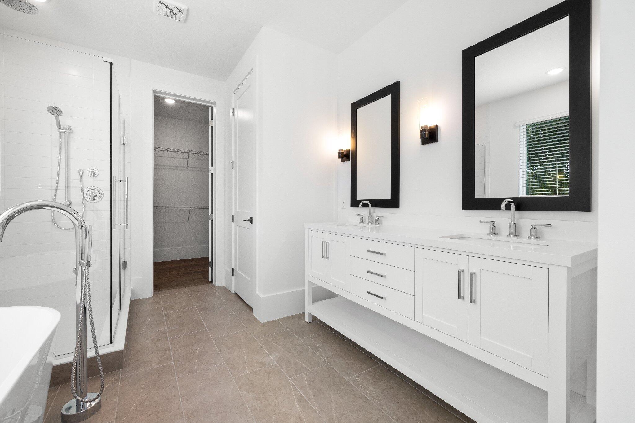 Double vanity featuring white cabinetry, a solid surface countertop, and dual rectangular mirrors with matte black frames